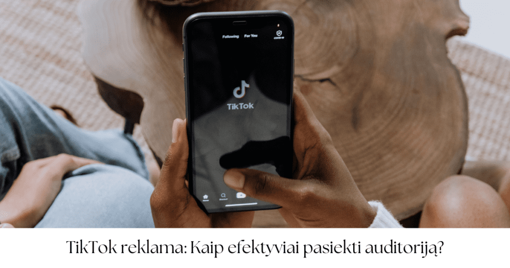 Asmuo laiko išmanųjį telefoną su atidaryta TikTok programėle ekrane