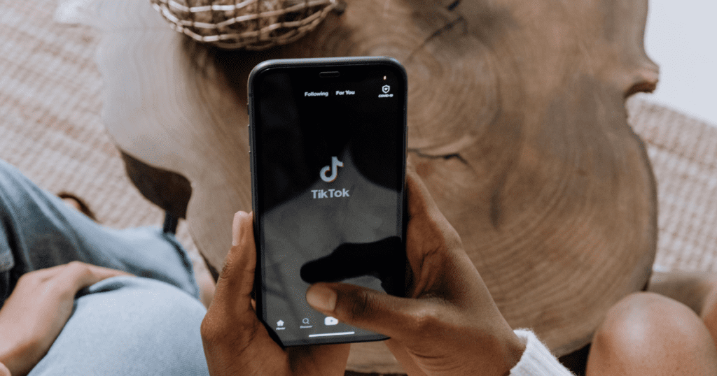 mergina laiko telefoną rankoje, kuriame įjungta TikTok programėlė